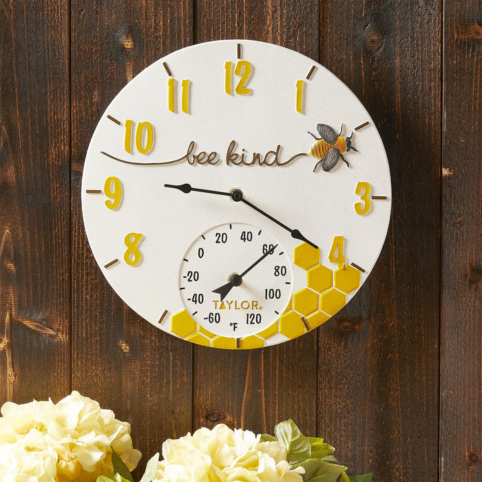 Bee Kind round poly resin clock with thermometer on a dark wood background, yellow hour markers and a bee illustration.