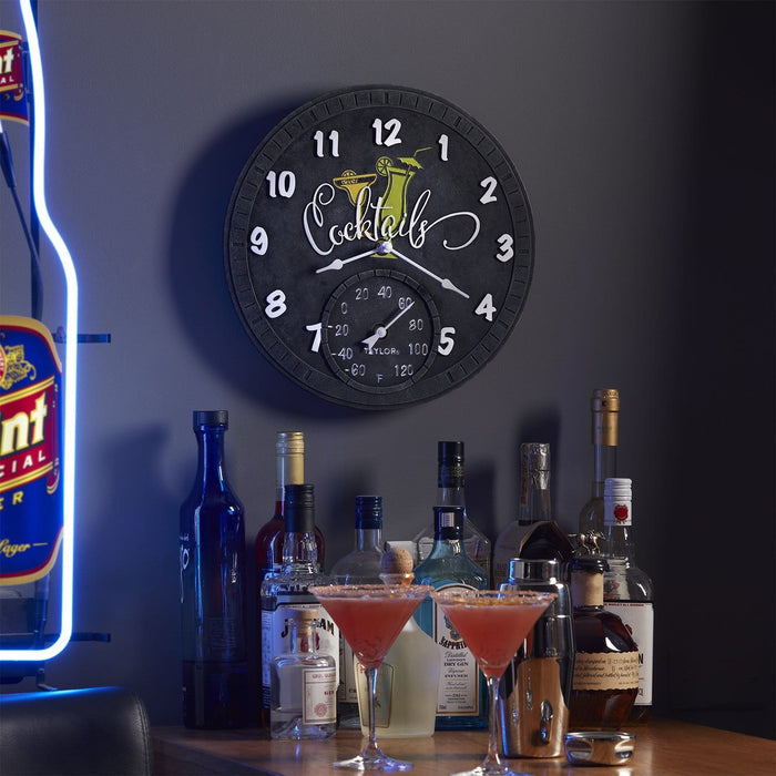 14 inch black Cocktails clock with thermometer on a bar wall beside liquor bottles and blue neon edge.