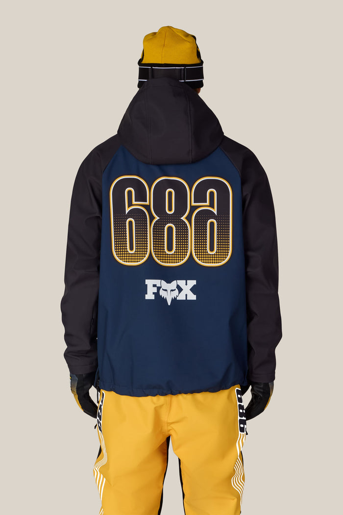 A person wearing a 686 Men’s Fox Racing Waterproof Hoody paired with yellow pants.