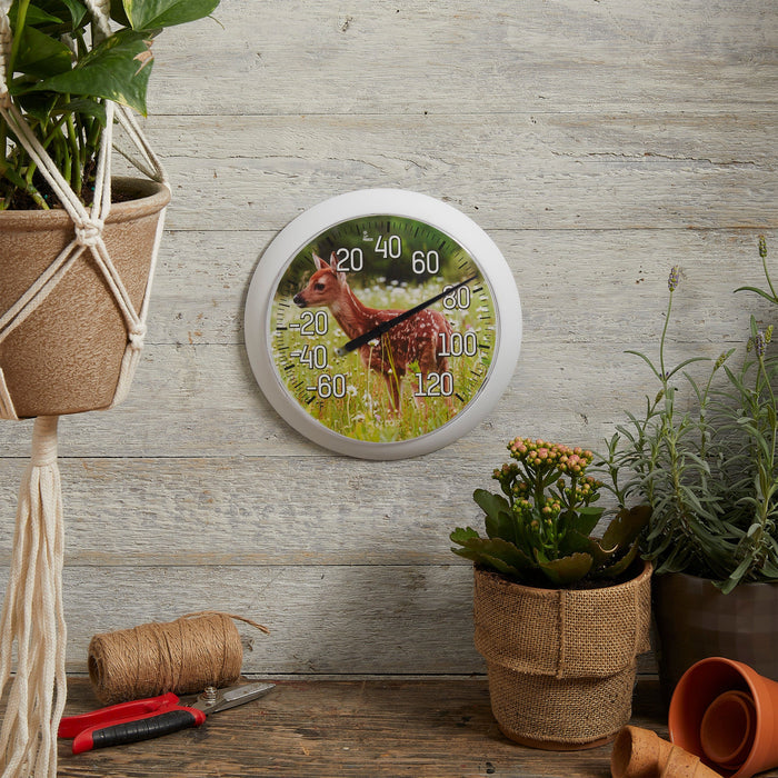 Sweet Fawn thermometer mounted on a weathered wooden wall beside potted plants and gardening tools