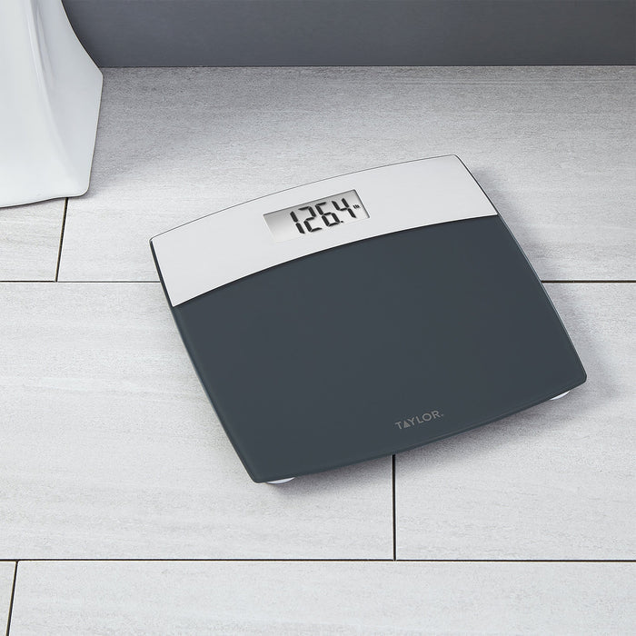 Top view of a grey digital glass kitchen scale with a brushed stainless steel tray on wood.