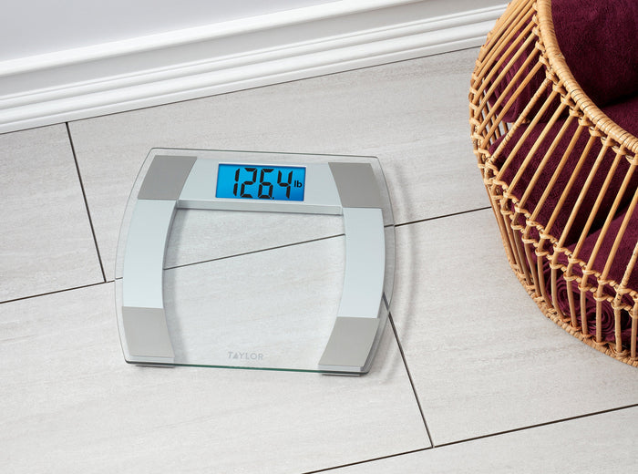 Digital glass bathroom scale on a light tiled floor showing 126.4 lb