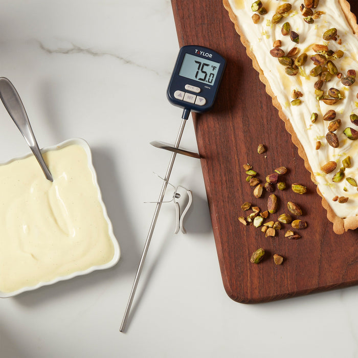 Taylor digital candy thermometer displaying 75.0°F beside a pistachio dessert on a wooden board