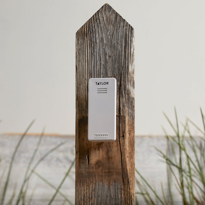 Taylor round digital thermometer mounted on a weathered wooden post with the transmitter nearby