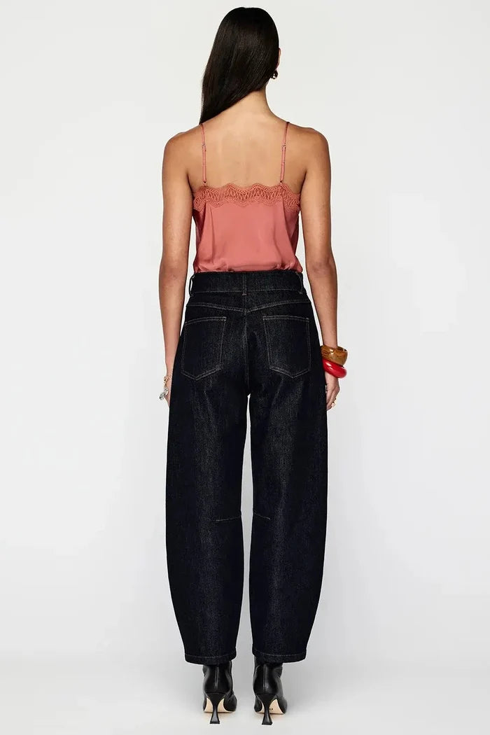 Woman wearing black high-waisted jeans and a pink top on a white background