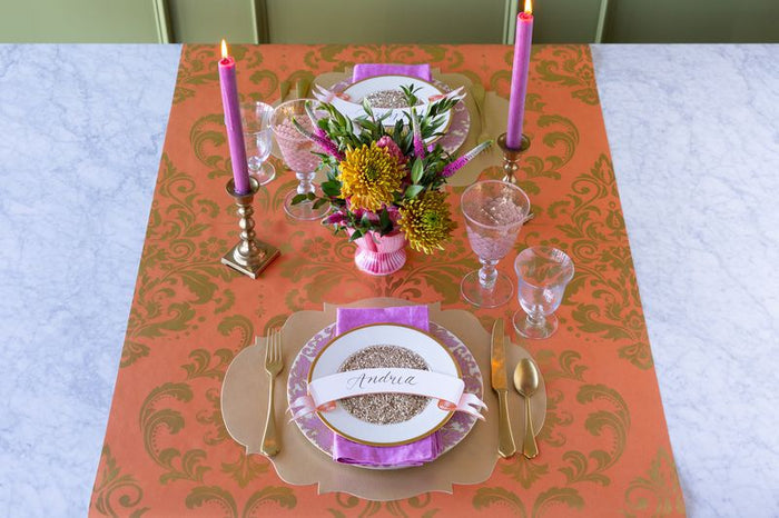 Elegant table setting with floral centerpiece, plates, and cutlery on a patterned tablecloth.