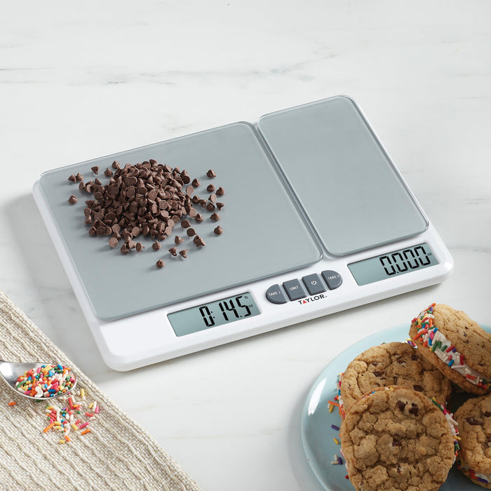 Top view of the kitchen scale with chocolate chips scattered on the left panel and cookies on a plate nearby