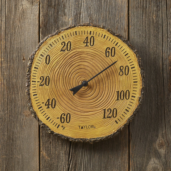 Front view of a wooden tree trunk cross section thermometer displaying a large Fahrenheit scale and black needle