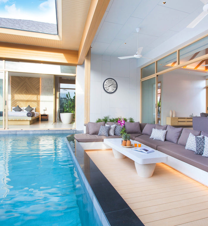 Modern outdoor living area with a pool and a round wall mounted thermometer on the wall