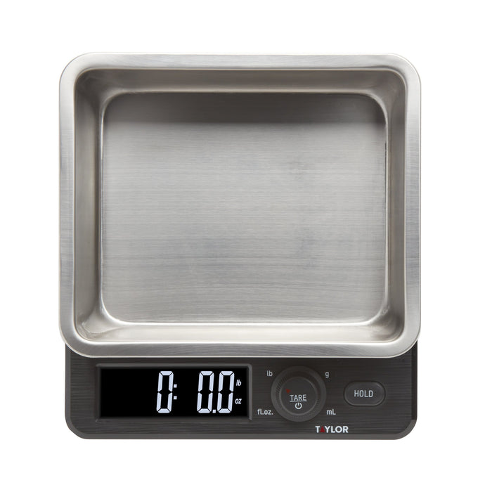 Close up of a Taylor 22 lb kitchen scale with a stainless steel storage container and lid.