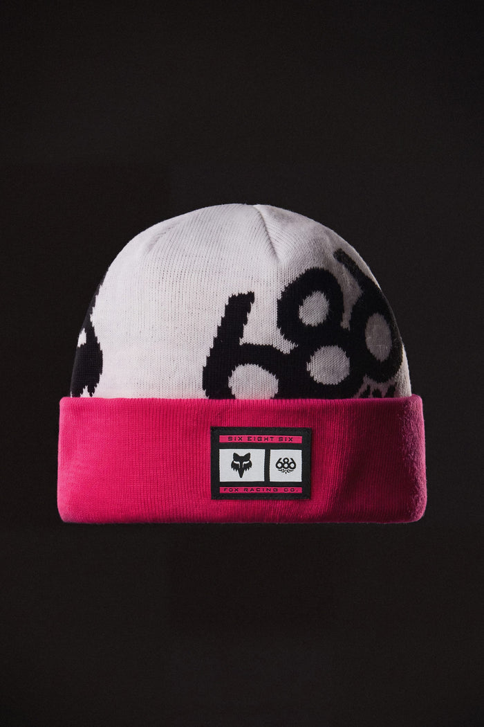 A white and pink 686 Fox Racing Cuff Beanie with a black branded patch on the cuff.