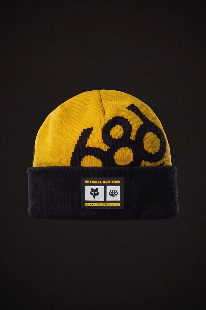 Yellow and black 686 Fox Racing Cuff Beanie featuring a collaborative brand patch on the front.