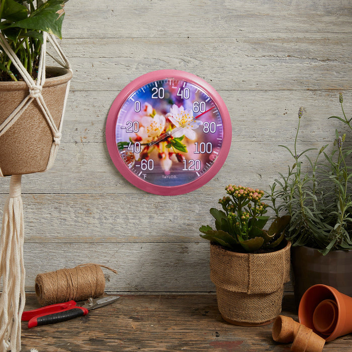 Pink Cherry Blossom thermometer on a rustic wooden table beside gardening tools and potted plants.