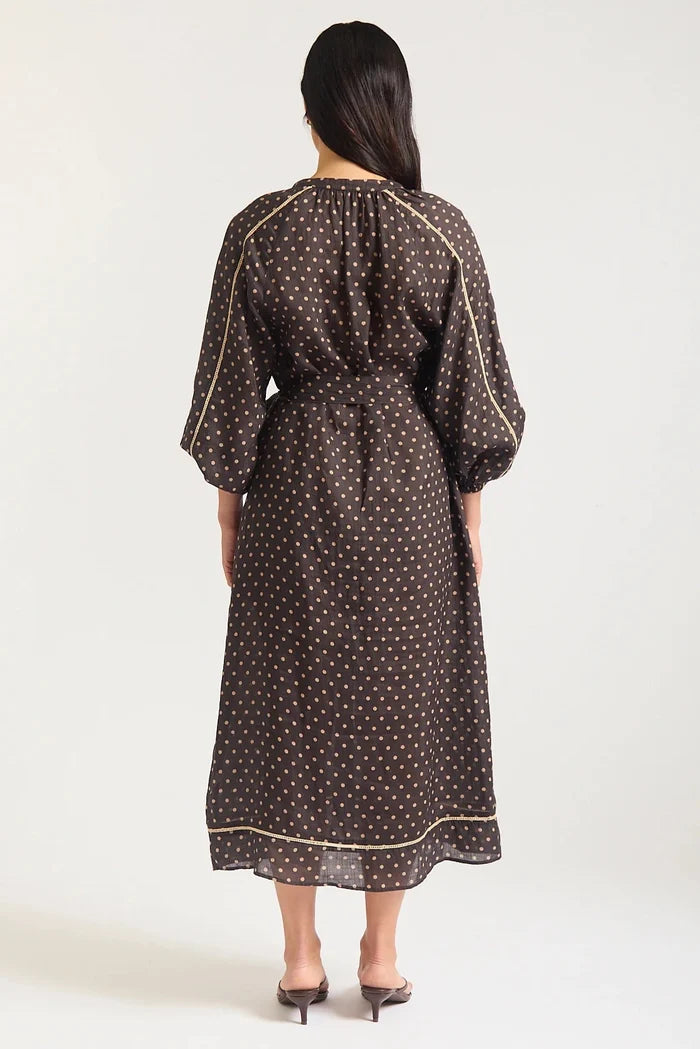 Woman wearing a black dress with white polka dots on a white background