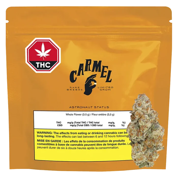 Front-facing shot of the golden pouch labeled "Carmel Astronaut Status" with a THC symbol at top left and a cannabis bud image overlapping the lower right.
