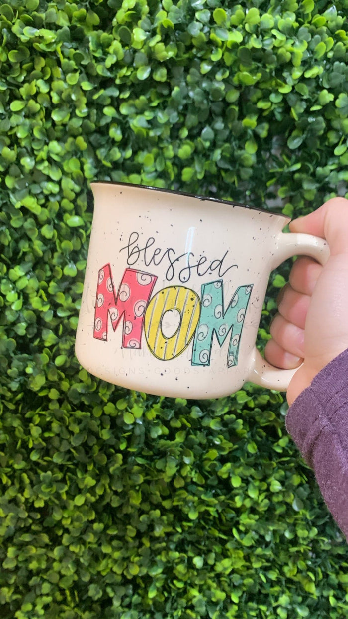 a white speckled mug with colorful text that reads "Blessed Mom"