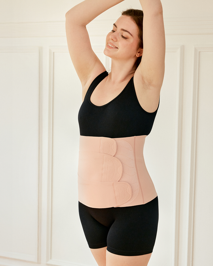 Momcozy Ergowrap Postpartum Belly Band in oyster pink color worn by a woman, featuring adjustable straps for postpartum support.