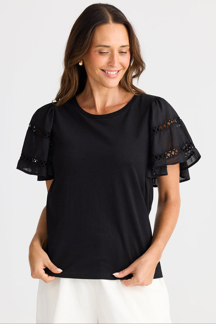 Woman wearing a black top with lace sleeves on a white background