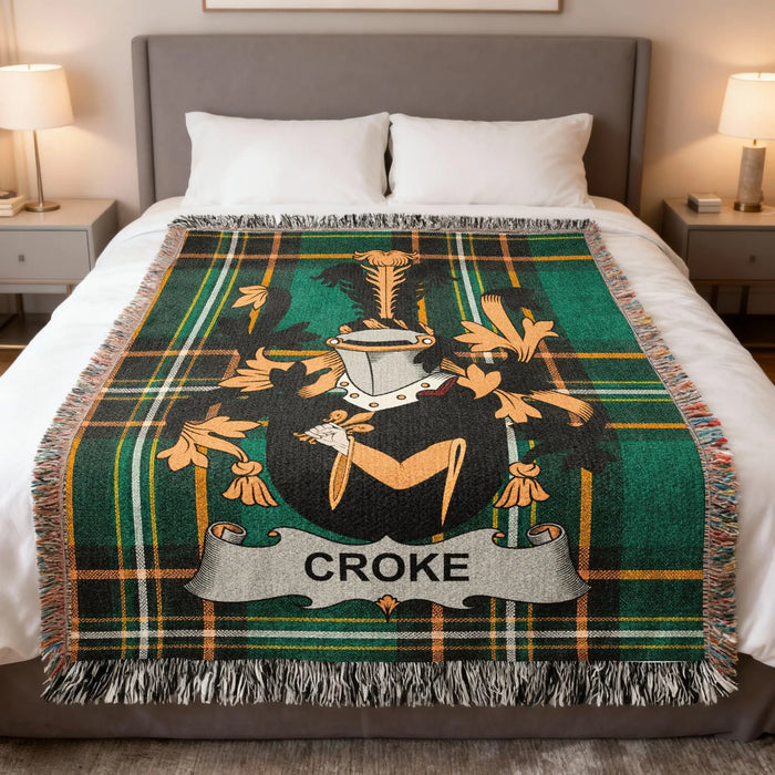 Croke family crest woven blanket arranged on a made bed.
