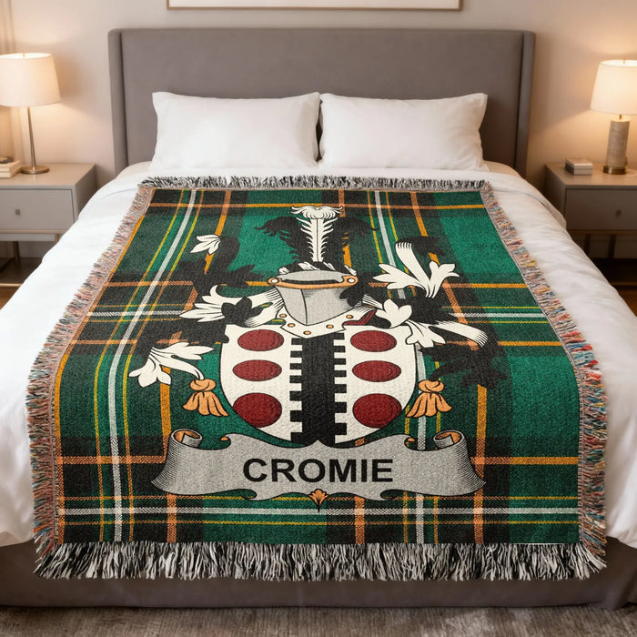 Cromie family crest woven blanket folded over a bed.