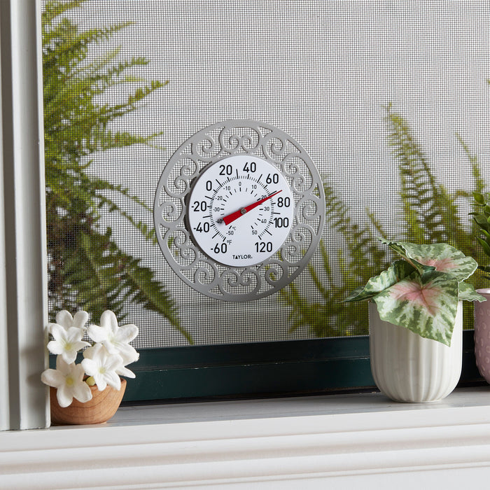 Outdoor view of the decorative magnetic thermometer mounted on a window screen with greenery nearby