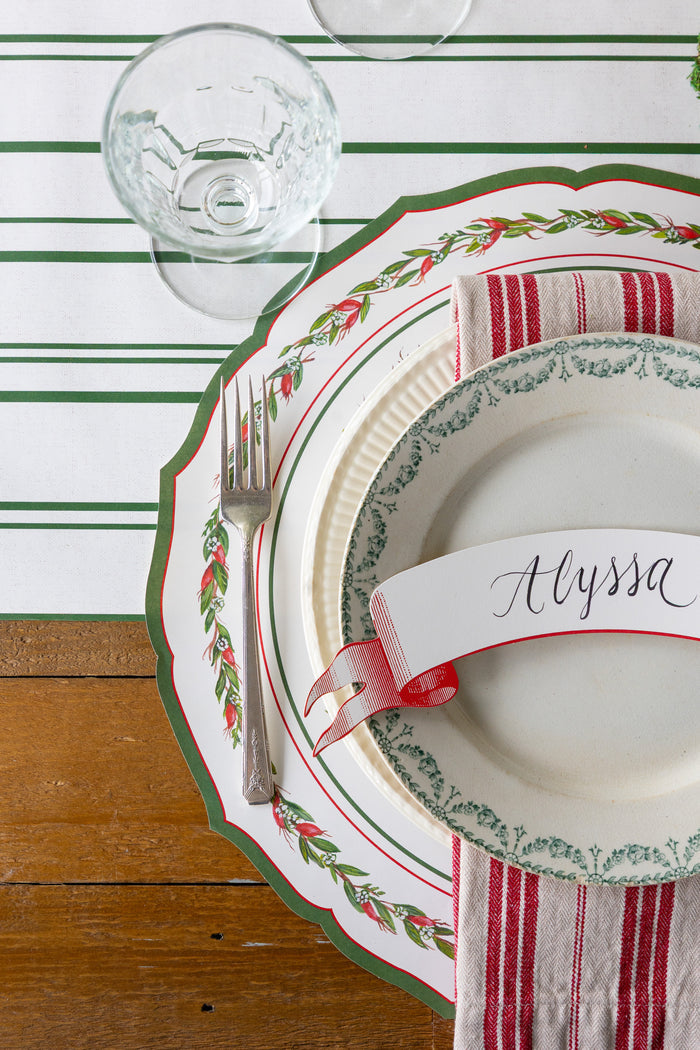 Christmas-themed place setting with a name card on a striped table runner.