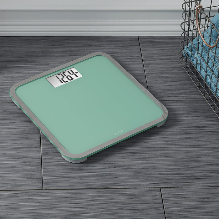 Seafoam green digital glass scale on dark wood floor with a metal basket nearby; weight display visible