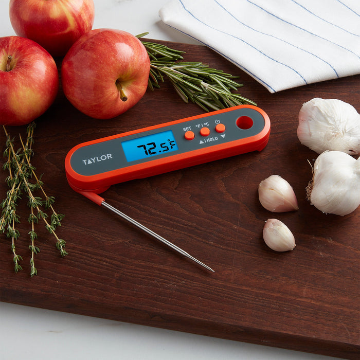 Red apples with rosemary on a wooden board and a folding probe thermometer at the edge.
