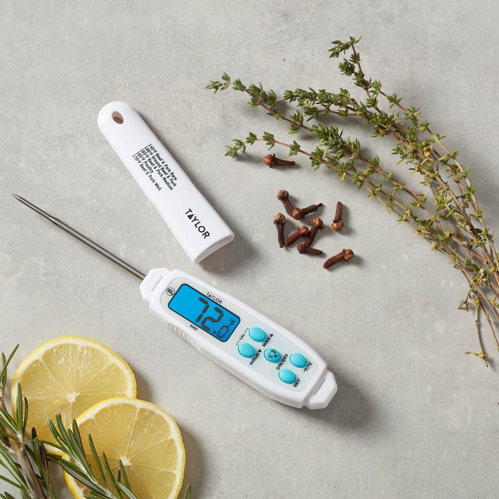 Taylor digital thermometer on a gray surface with lemon slices and rosemary sprigs nearby