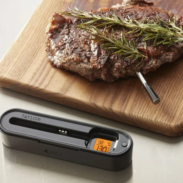 Taylor digital meat thermometer in use with steak on a cutting board and orange display