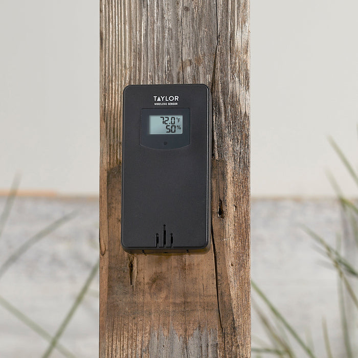 Taylor wireless thermometer mounted on a weathered wooden post outdoors with its display visible