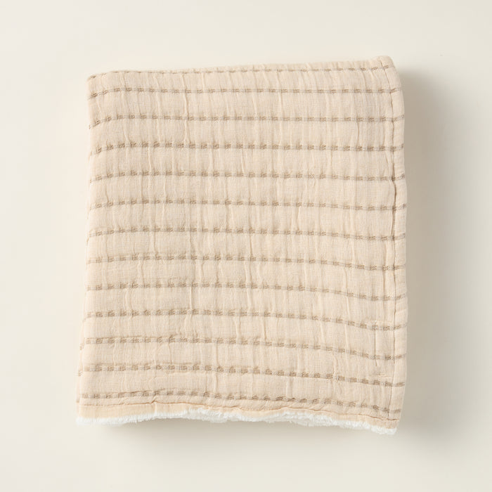 Two-tone double gauze cotton throw blanket on a sofa, with a neutral and brown side.