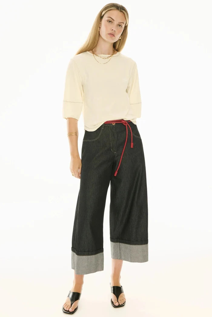 Woman wearing a cream sweater and black wide-leg pants with a red drawstring on a white background