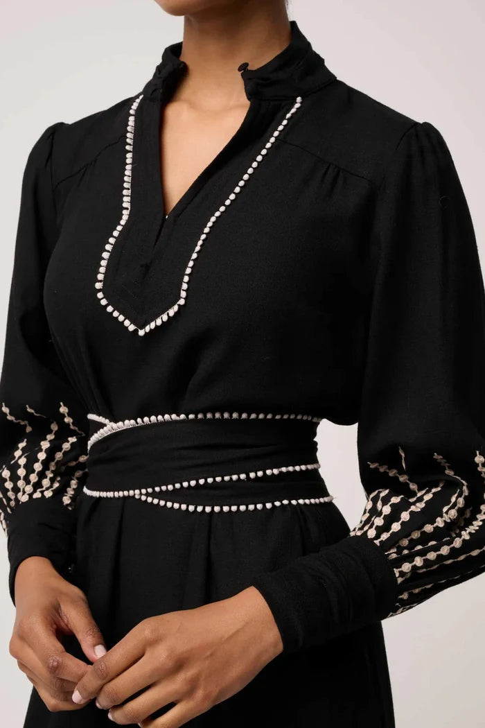 Black dress with intricate white detailing on a plain background