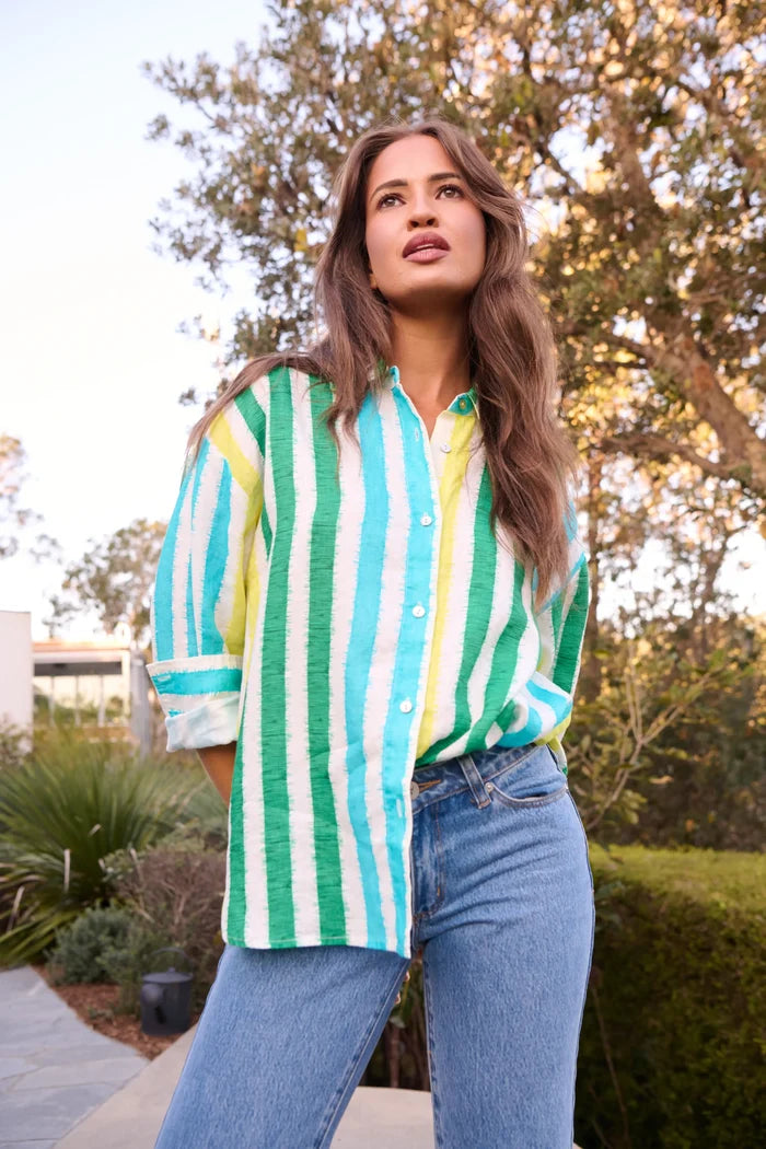 Woman wearing a green and white striped shirt with blue jeans outdoors.