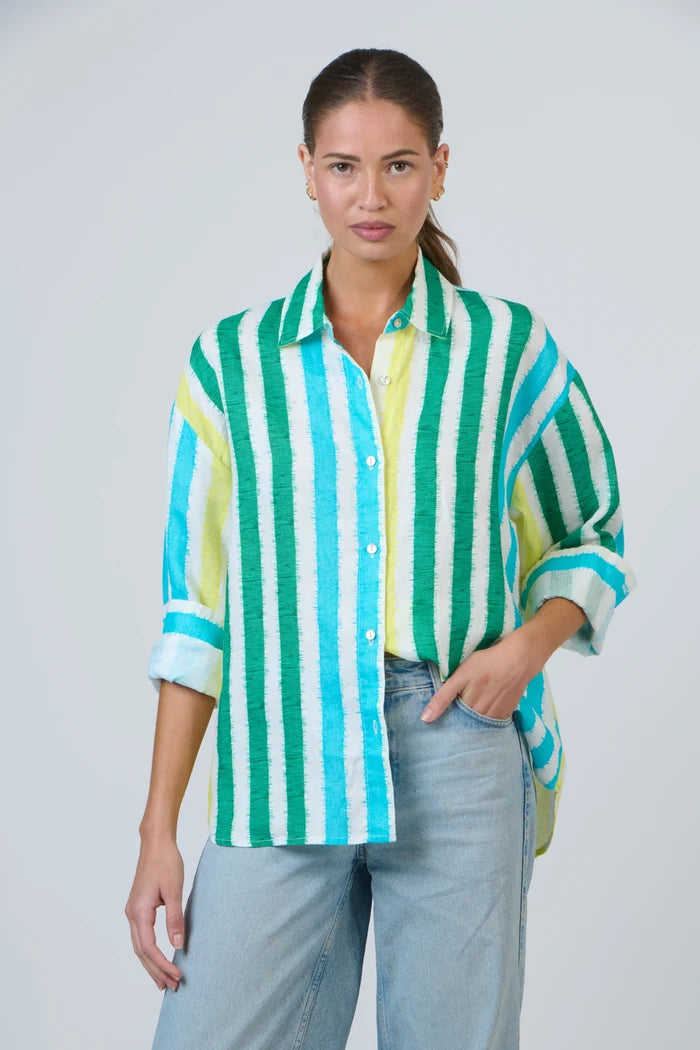 Woman wearing a green and blue striped shirt with light blue jeans on a white background