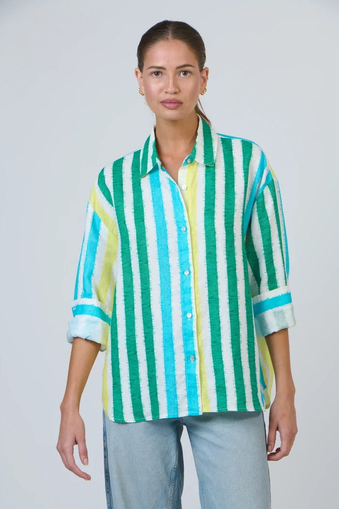 Woman wearing a green and blue striped shirt against a plain background