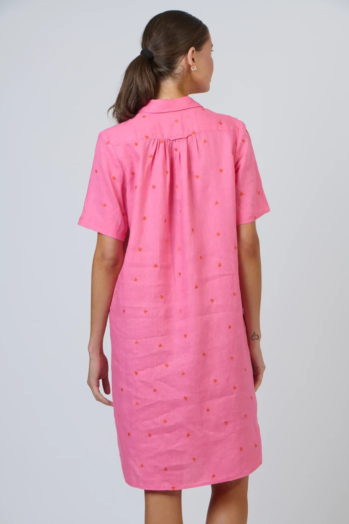 Person wearing a pink dress with a subtle pattern on a plain background