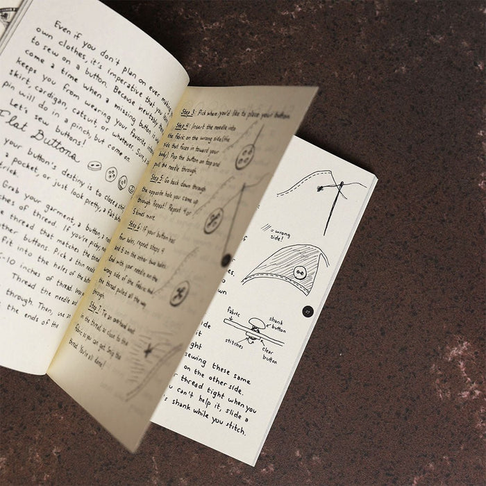 Open book with handwritten text and illustrations on a dark surface