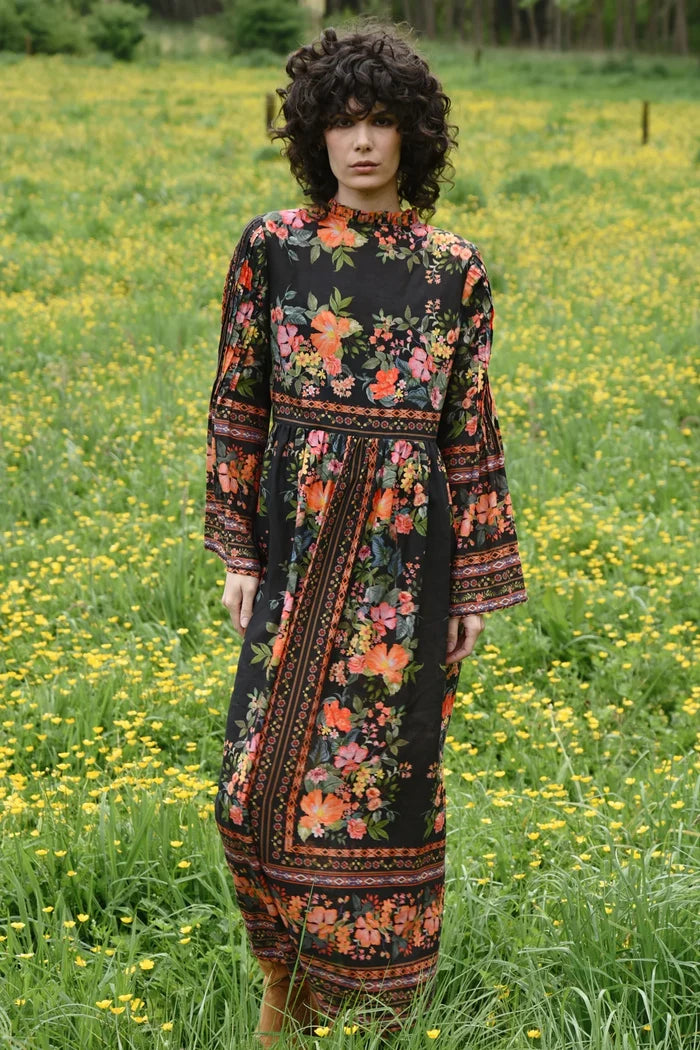 Woman in a floral dress standing in a field of yellow flowers