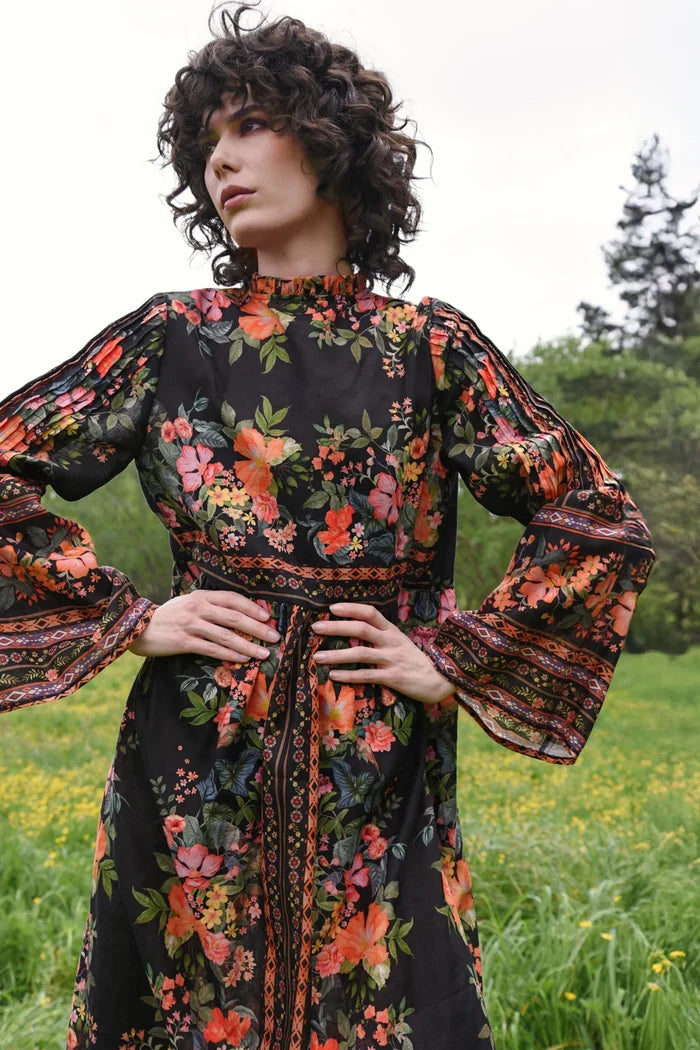 Woman wearing a floral dress in a natural setting with trees and grass.