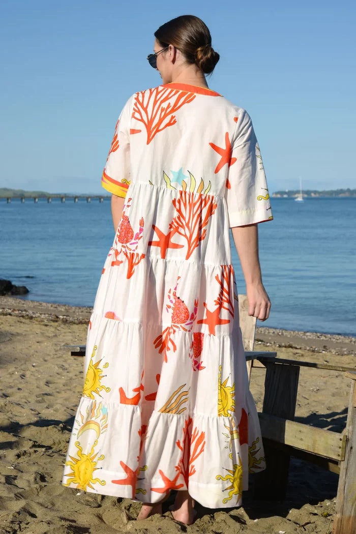 Woman wearing a colorful dress with a floral pattern on a beach.