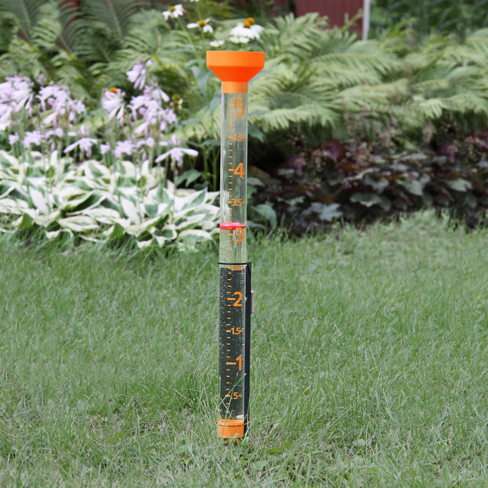 Jumbo Easy-View Rain Gauge with bright orange funnel top in a garden setting.