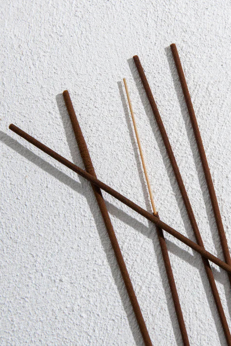 Five incense sticks on a textured white surface
