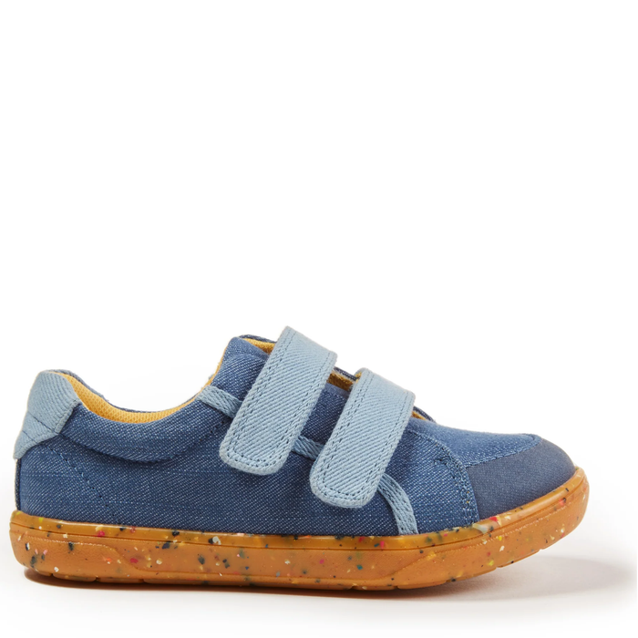 A child's denim sneaker with blue velcro straps and a brown speckled sole.