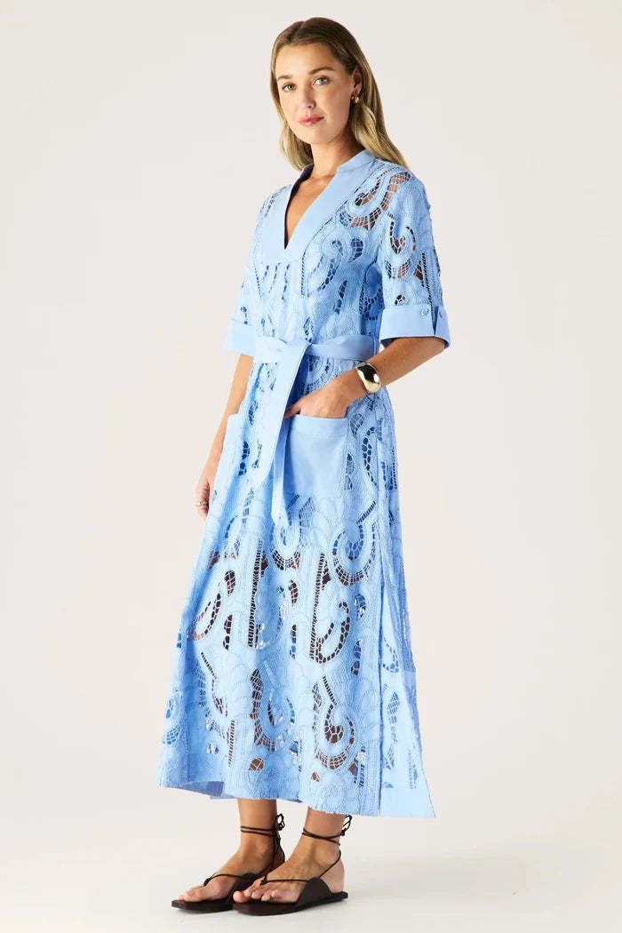 Woman wearing a light blue dress with a pattern on a white background