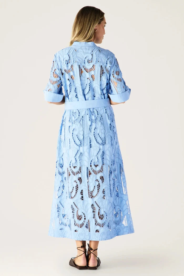 Woman wearing a light blue dress with lace details on a white background
