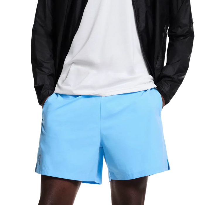 Man wearing a black jacket, white t-shirt, and light blue shorts on a white background