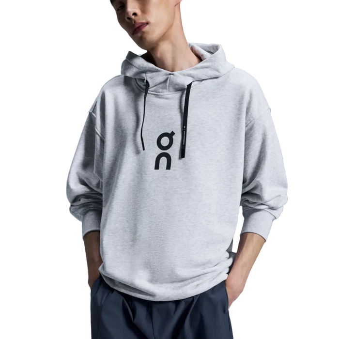 Man wearing a gray hoodie with a logo on a dark background
