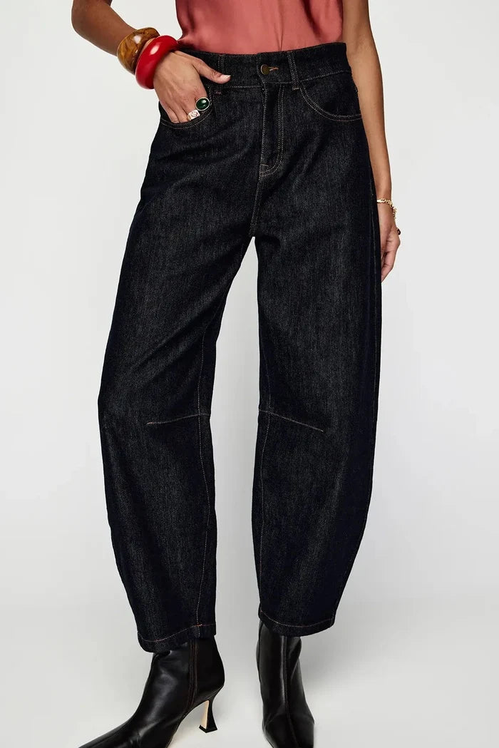 Person wearing dark blue jeans and black boots on a white background